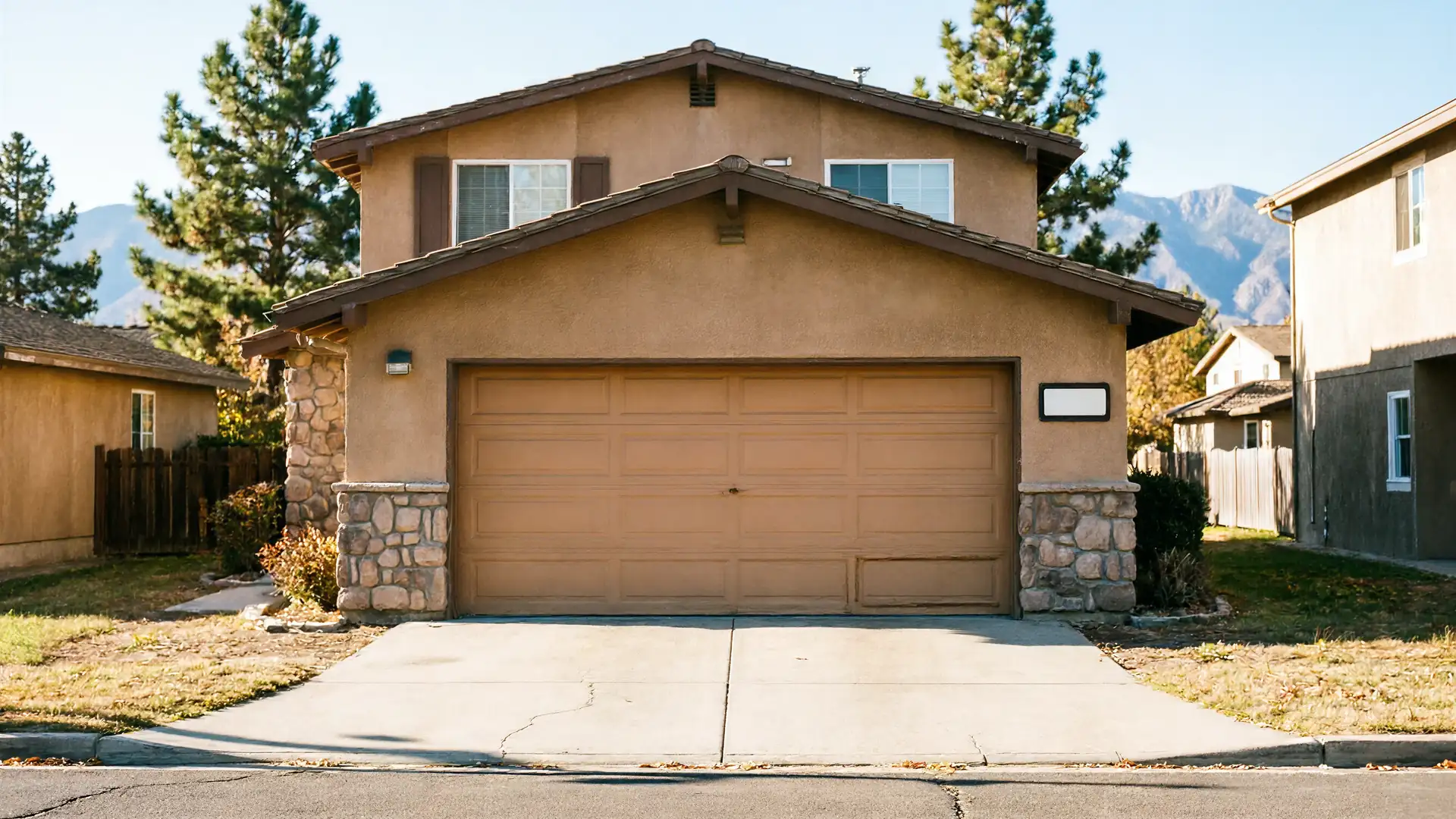 The house has a brown garage door, tan stucco, and stone accents.